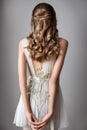 Photo from the back of a very beautiful young model in white dress with gypsophila flowers in her hands. Romantic style.