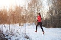 Photo from back of woman in sports uniform on morning run in winter forest Royalty Free Stock Photo