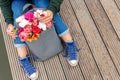 Photo from the back of young blonde dreamy woman with bouquet of flowers in grey backpack near a river. romantic mood Royalty Free Stock Photo