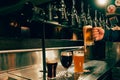 Photo of bartender pouring cold foamy beer from tap into glass at bar with multiple beer dispensers. Serving craft beer Royalty Free Stock Photo