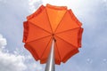 Photo of a beach umbrella on the blue sky,Beach umbrella.One vibrant orange colored sunshade against vivid blue sky and white Royalty Free Stock Photo