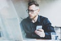 Photo bearded adult hipster working on modern urban cafe. Man wearing black shirt and holding contemporary smartphone