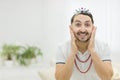 Photo of bearded man touching his face wearing childish crown.