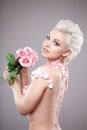 Photo of a beautiful blond woman with flower. Closeup attractive sensual face of white woman with curly hair. Smokey eye Royalty Free Stock Photo