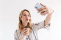 Photo of beautiful blonde woman wearing glasses taking selfie photo on smartphone Royalty Free Stock Photo