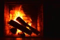 Photo with beautiful brick fireplace with firewood burning in fire and with place for greeting inscription on dark