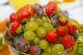 Photo of beautiful and delicious fruits and berries, grapes, strawberries and plums lying heaped in a round glass vase. Royalty Free Stock Photo