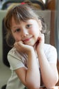 Photo of beautiful European cute girl traveling on train, holding hands near face. Close-up of a happy child looking at camera Royalty Free Stock Photo