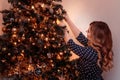 Beautiful girl in a blue dress decorates a Christmas tree in the evening Royalty Free Stock Photo