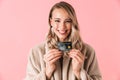 Happy excited young pretty woman posing isolated over pink wall background holding credit card