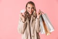 Beautiful happy excited young pretty woman posing isolated over pink wall background holding shopping bags and credit card Royalty Free Stock Photo