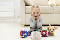 Photo of beautiful little girl looking surprised into the camera lying on the floor with soft toys. Royalty Free Stock Photo