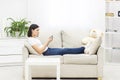 Photo of beautiful mother lying on sofa in living room and holding phone. Royalty Free Stock Photo