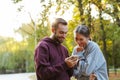 Photo of beautiful pleased couple using cellphone and laughing