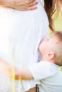 Beautiful pregnant woman in white dress on the meadow with her son Royalty Free Stock Photo