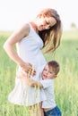 Beautiful pregnant woman in white dress on the meadow with her son Royalty Free Stock Photo