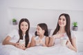 Photo of beautiful pretty three sisters sleepwear sitting bed having rest laughing drinking morning beverages inside