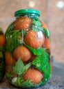 Beautiful red tomatoes and green spices in a glass jar, canned vegetables, tomato pickling, winter products, healthy food,