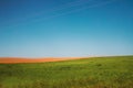 Beautiful rural landscape with on a green and brown plowed field on a background of blue sky