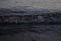 Photo of a beautiful sunny day. Late evening, sunset, tide. A beautiful strong wave runs on the sandy shore of the sea.