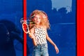 Beautiful teenage girl inflates soap bubbles in front of the red-blue wall Royalty Free Stock Photo