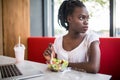 Beautiful woman have lanch eat salad at dinner sitting at cafe. Young african american woman sitting in a coffee shop and working Royalty Free Stock Photo