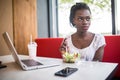 Beautiful woman have lanch eat salad at dinner sitting at cafe. Young african american woman sitting in a coffee shop and working Royalty Free Stock Photo