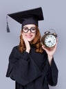 photo of beautiful young alumnus with alarm clock on the wonderful grey studio background