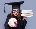 photo of beautiful young alumnus with pile of books on the wonderful grey studio background