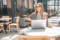 Photo of beautiful young pretty 30s woman sitting in cafe indoors using laptop computer and mobile phone looking at Royalty Free Stock Photo