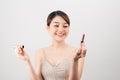 Photo of a beautiful young pretty asian woman with healthy skin posing naked isolated over white wall background holding lipstick Royalty Free Stock Photo