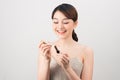 Photo of a beautiful young pretty asian woman with healthy skin posing naked isolated over white wall background holding lipstick Royalty Free Stock Photo