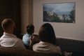 A photo from behind of a family which is watching a movie on a widescreen TV set Royalty Free Stock Photo