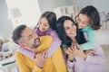 Photo of big family four members parents hold piggy back children look eyes wear colorful jumper in living room indoors Royalty Free Stock Photo