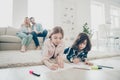 Photo of big family two children lying floor fluffy carpet making drawings while parents enjoy watching friendly adopted