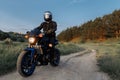 Photo of biker driving motorcycle in sunset on the country road.