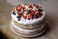 naked cake with a white cream strawberries blueberries and a white chocolate