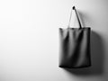 Photo black cotton textile bag hanging right side. Empty white wall background. Highly detailed texture, space for