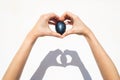 Photo of a black egg in hands with a shadow cast on a white background. Royalty Free Stock Photo