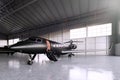 Photo of Black Matte Luxury Generic Design Private Jet parking in hangar airport. Concrete floor. Business Travel