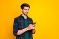 Photo of blogger guy holding telephone in hands checking subscribers wear casual checkered shirt isolated yellow color Royalty Free Stock Photo