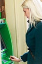 Photo of blonde in coat at green cash machine Royalty Free Stock Photo