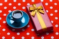 Photo of blue cup of coffee and cute gift on the red dotted back Royalty Free Stock Photo