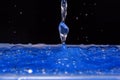 Photo of blue water trickle and drops on black background