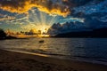 Boat on the sea at incredible sunset with sun rays coming out between clouds in Ilhabela - Sao Paulo, Brazil