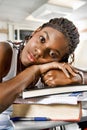 Portrait of Bored young African American woman resting on stack of books in classroom Royalty Free Stock Photo