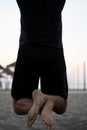 Bottom of young man suspended in a bar doing chin ups