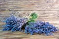 Closeup photo of a bouquet of lavender, tied with a rough rope, lying on another bouquet of lavender on a wooden background
