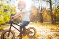 Photo of boy in helmet on running bike in autumn park