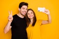 Photo of boyfriend and girlfriend smiling toothily cheerfully traveling around the world showing v-sign taking selfie Royalty Free Stock Photo